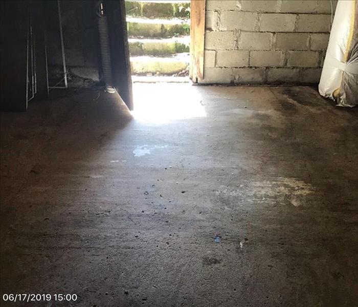 The concrete floor is drylooking, the door to the outside is open