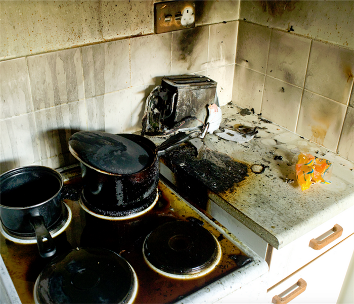 a fire damaged kitchen with soot covering the counter and the walls by the stove